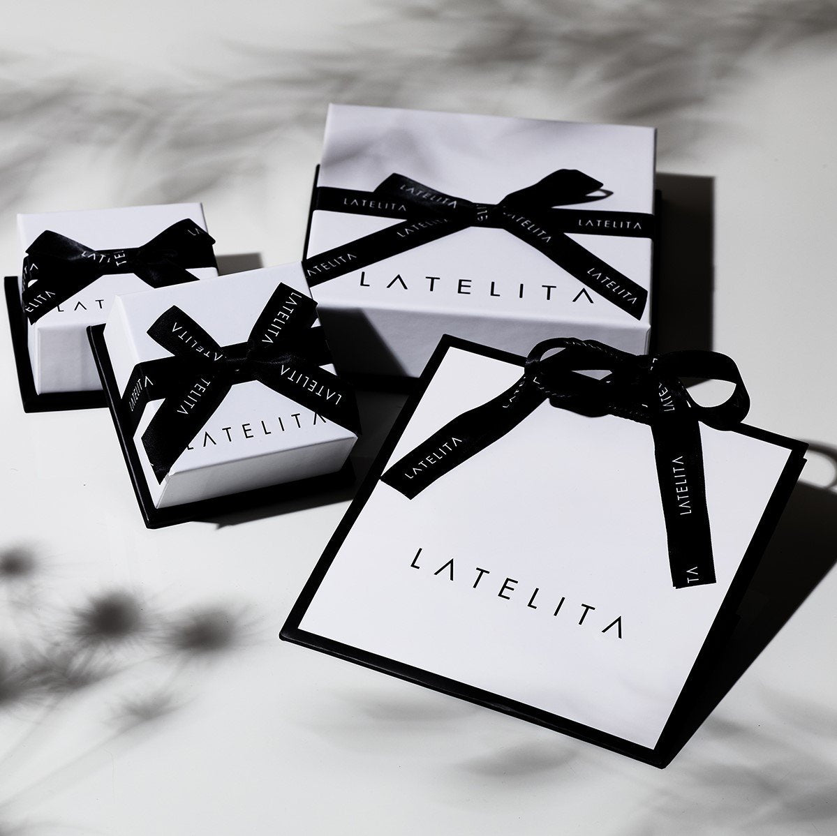 Gift boxes with black ribbons and 'LATELITA' branding on a light background.