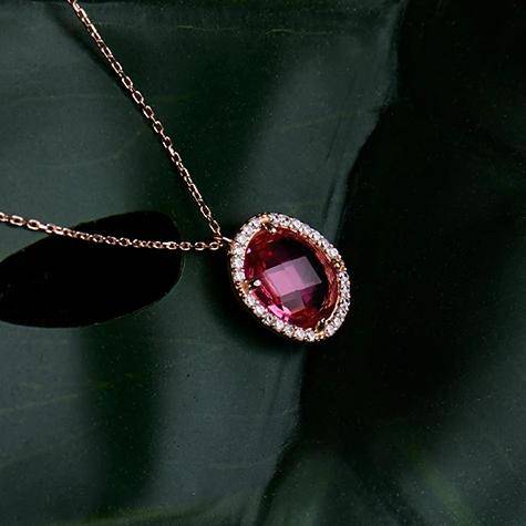 Necklace with red gemstone pendant on green background